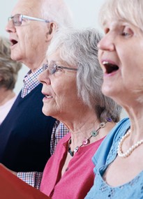 Zwei ältere Frauen und ein älterer Mann singen gemeinsam.
